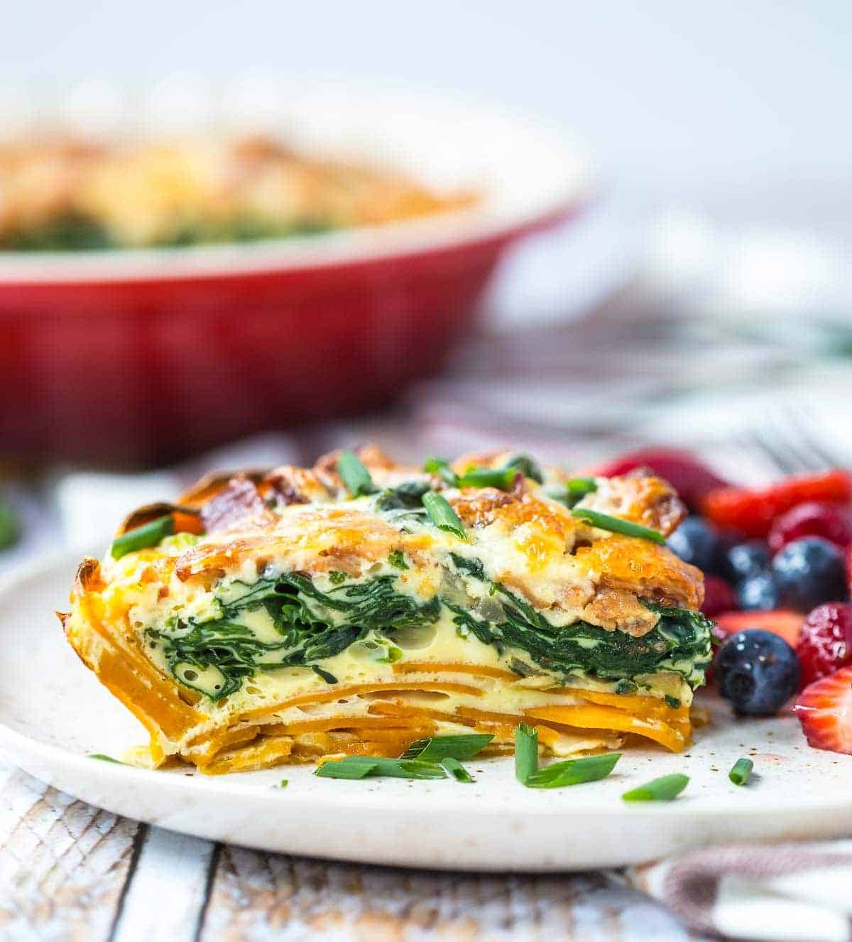 Side view of a serving of quiche on plate with fresh berries on the side.