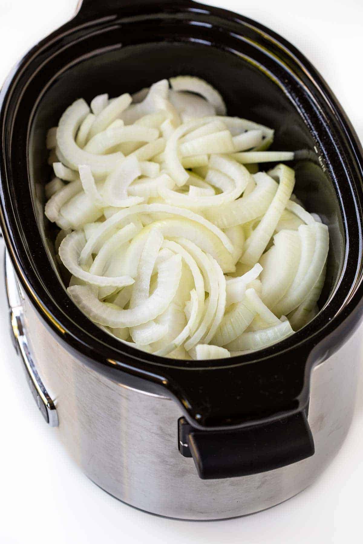 Uncooked onions in a crockpot.