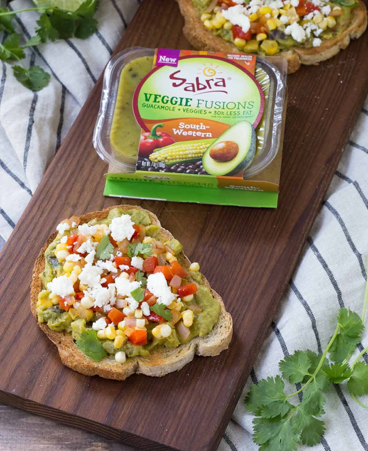 Package of Sabra Veggie Fusions Guacamole on board with toasts.