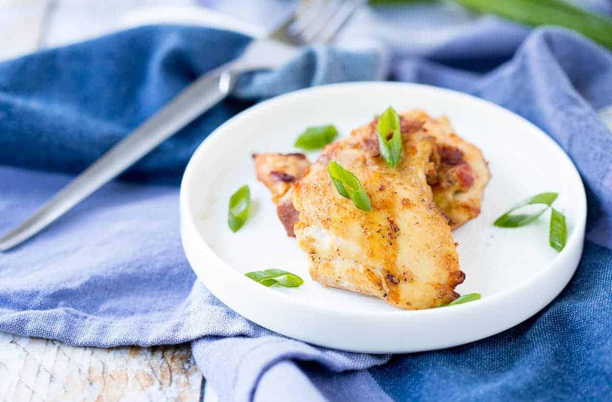 Grilled chicken on small white plate, with fork and blue napkin.