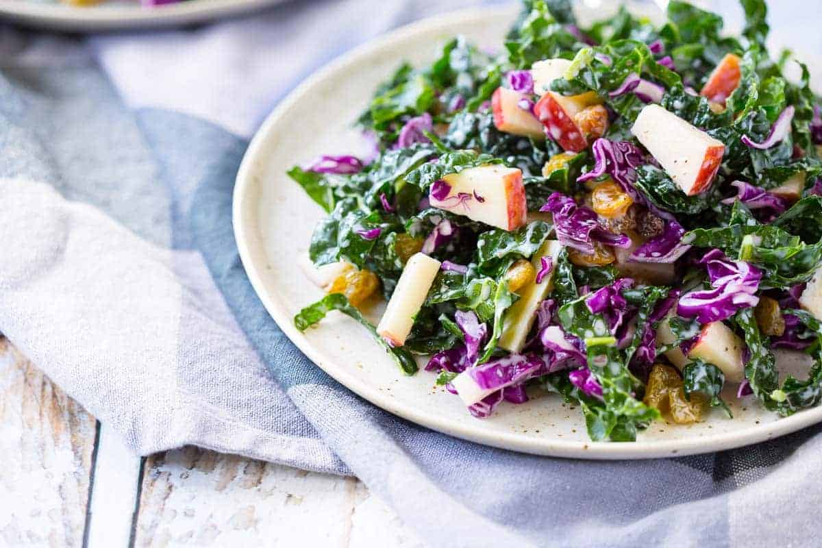 Front view of plated kale salad on blue and white striped cloth.