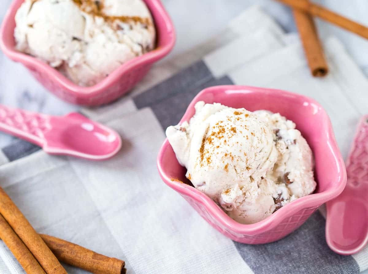 Pink decorative bowls containing ice cream, along with pink cone shaped spoons.