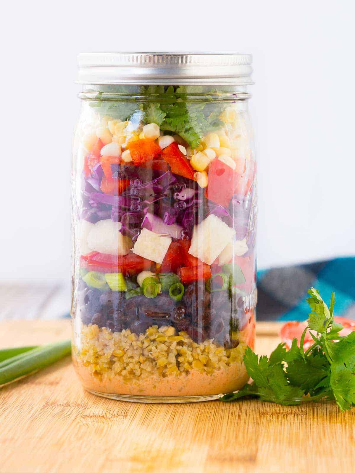 Chopped salad in a tall mason jar.