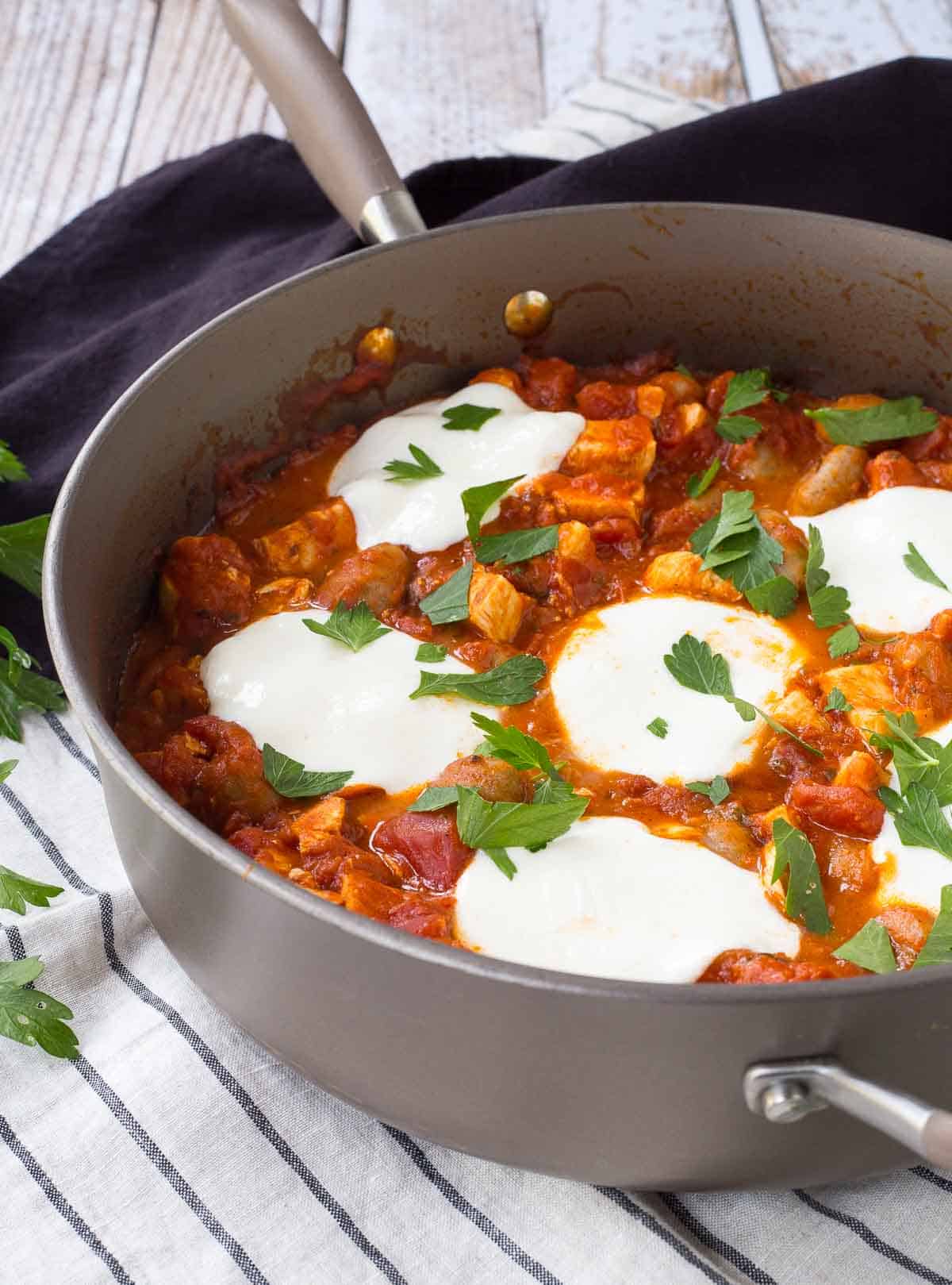 Partial image of large skillet containing gnocchi with chicken and tomato sauce.