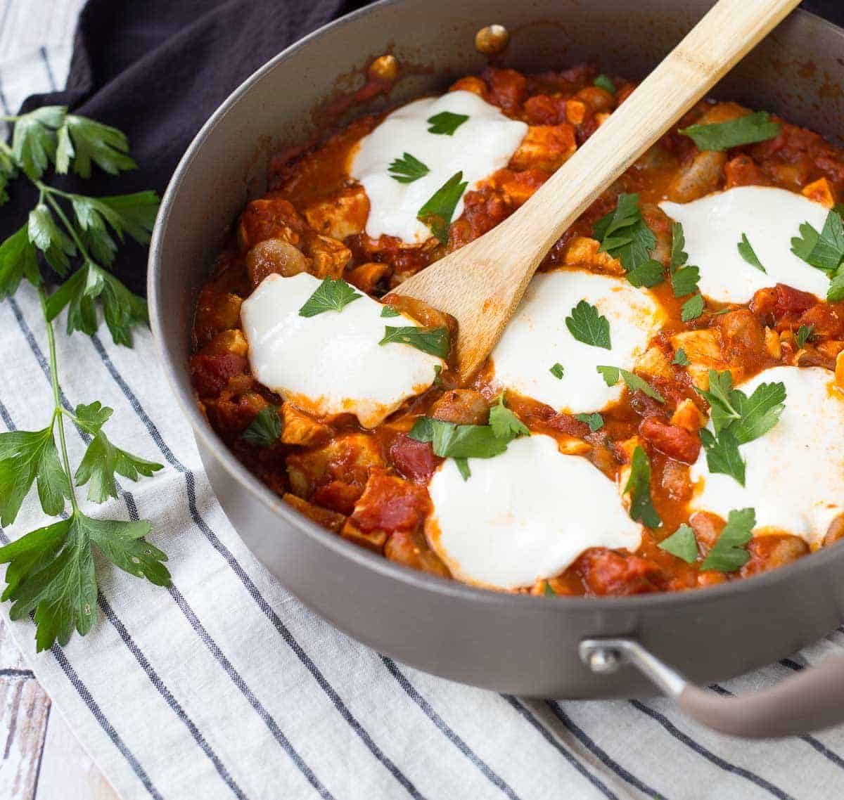 Skillet with wooden spoon inserted into gnocchi dish.