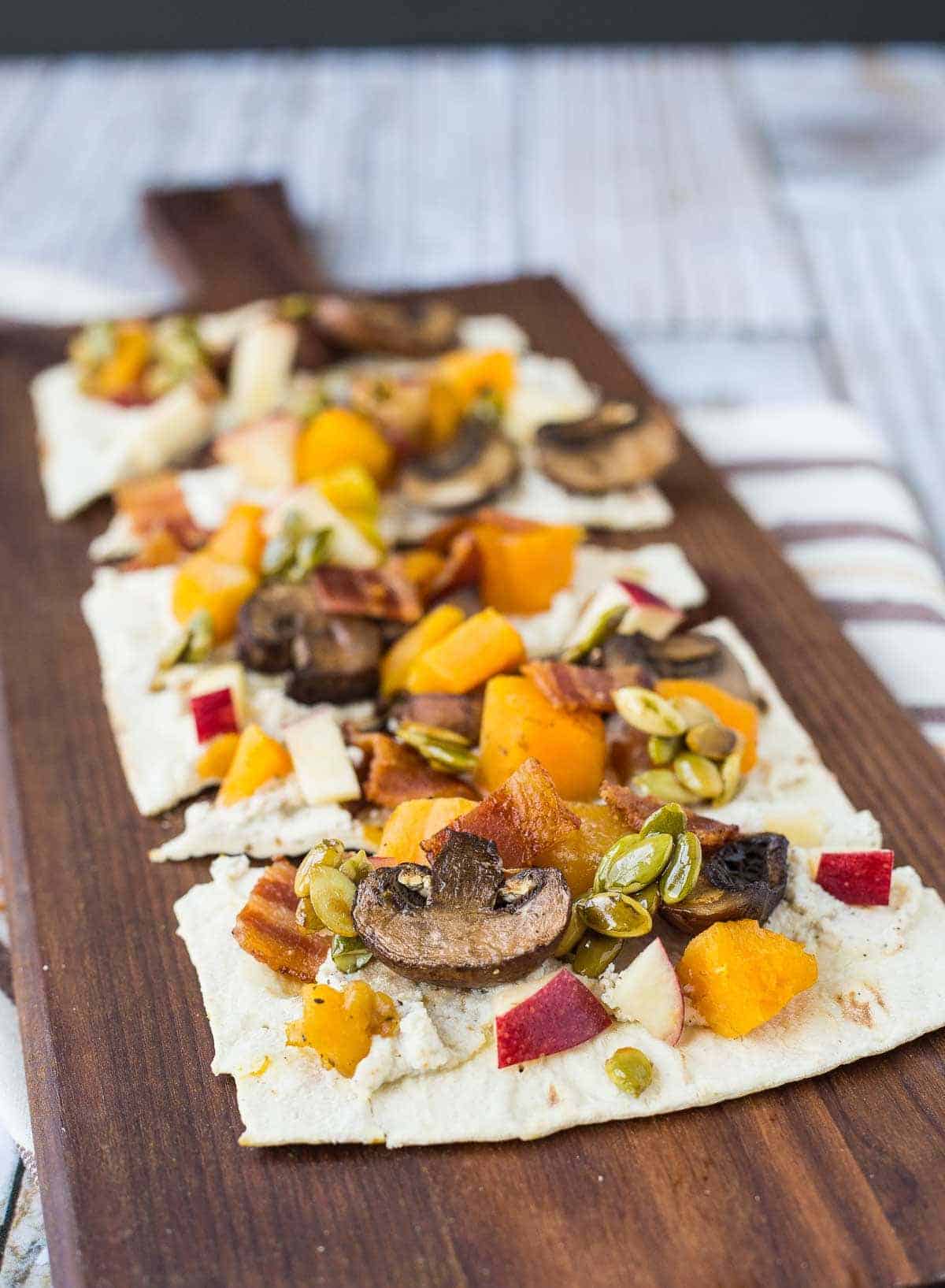 Close up of flatbread pizzas on wooden board. 