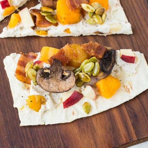 Experience a taste of fall with this ricotta flatbread! The party starts in the spiced ricotta and carries throughout the fun autumn toppings: bacon, squash, apples, mushrooms, and maple candied pepitas. You'll want to eat this all year! Get the easy recipe on RachelCooks.com!