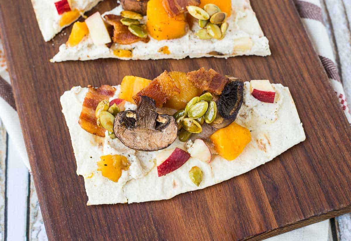 partial image of ricotta flatbread on wooden board.