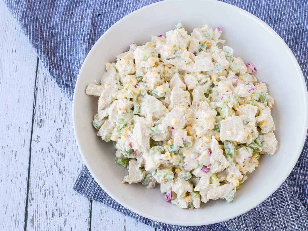 Overhead of green chile chicken salad ingredients, mixed together in shallow white bowl.