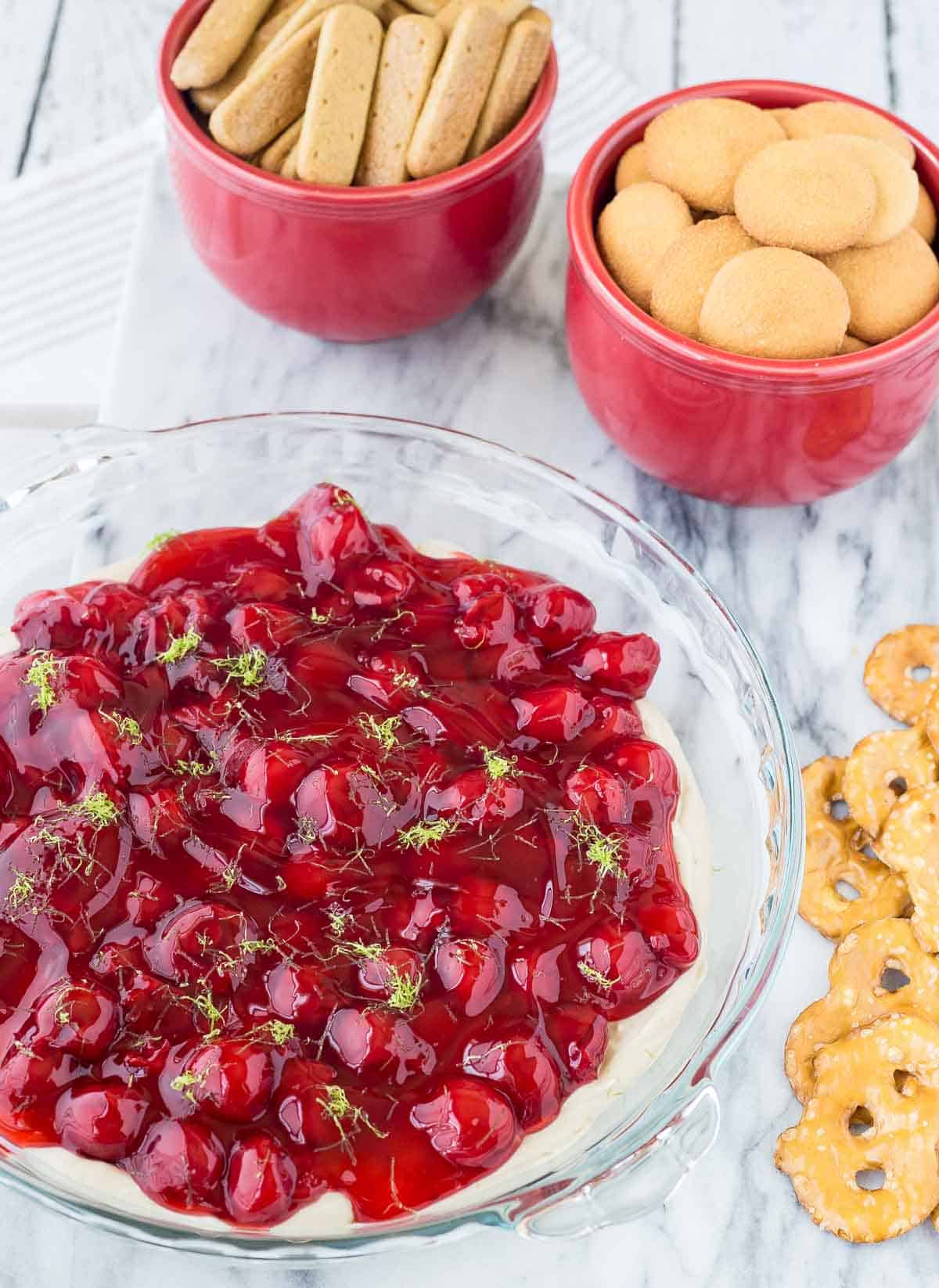 Cherry cheesecake in a pie pan with dippers around it.