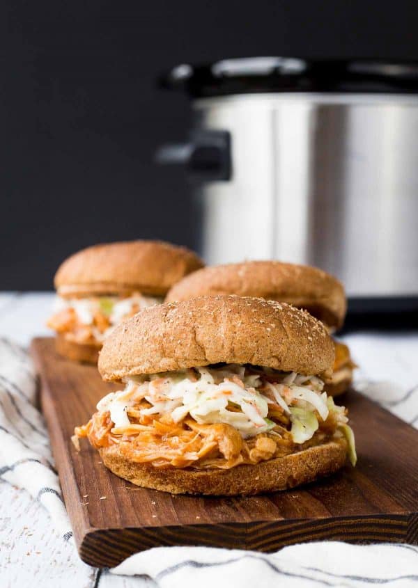 Filled buns with pulled pork and cole slaw on wooden board.