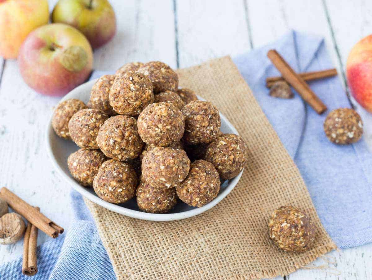 A bowlful of energy bites with apples and cinnamon sticks.