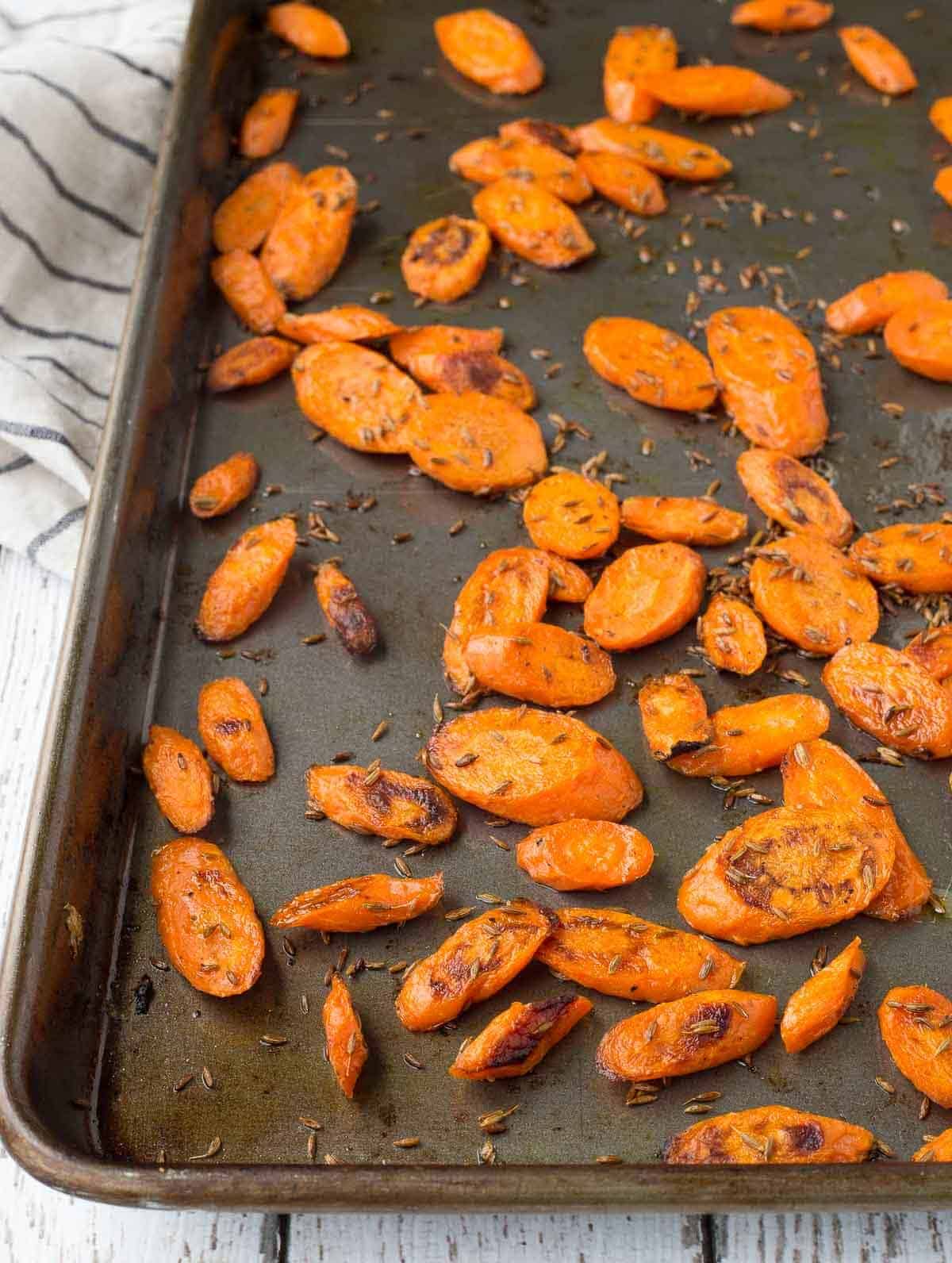 Carrots roasted with cumin seeds, on a sheet pan.