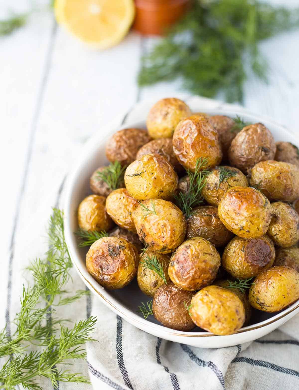 Overhead of dill potatoes in round white serving dish.