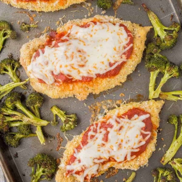 Overhead of chicken Parmesan with broccoli on sheet pan.