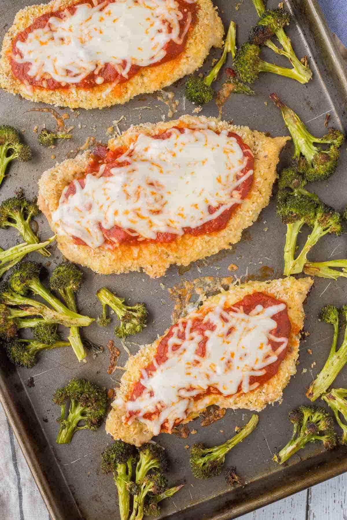 Overhead of chicken Parmesan and broccoli on sheet pan.