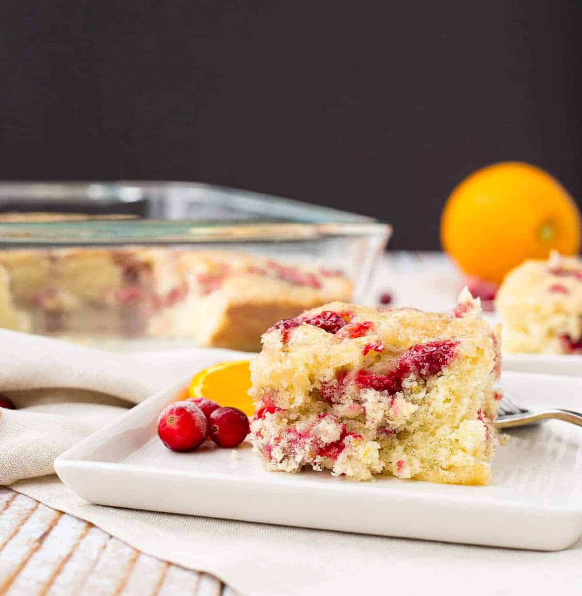 Front view of a piece of coffee cake, with remainder in clear glass baking dish in background.