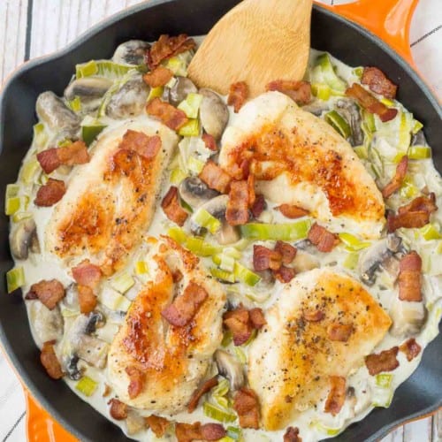 Overhead of chicken with sauce in orange skillet, garnished with bacon.