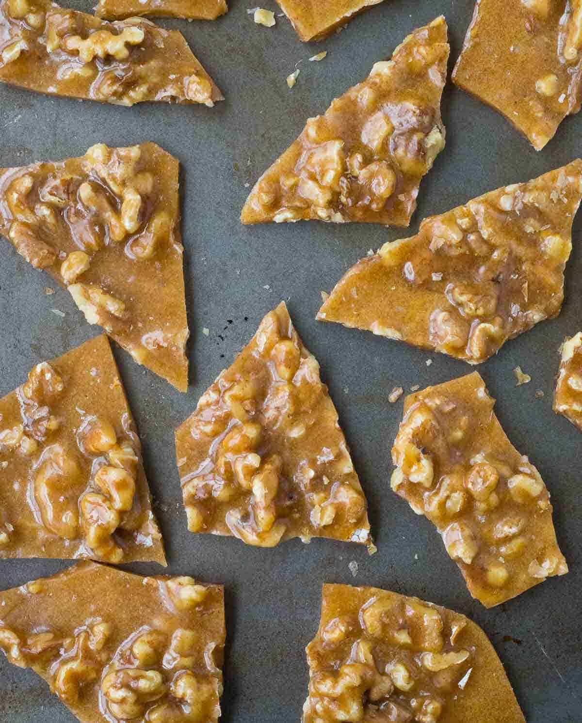 Pieces of walnut brittle on a grey background.