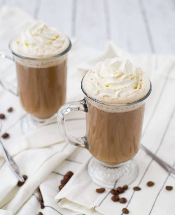 Front overhead of 2 glass mugs containing White Russian drink.