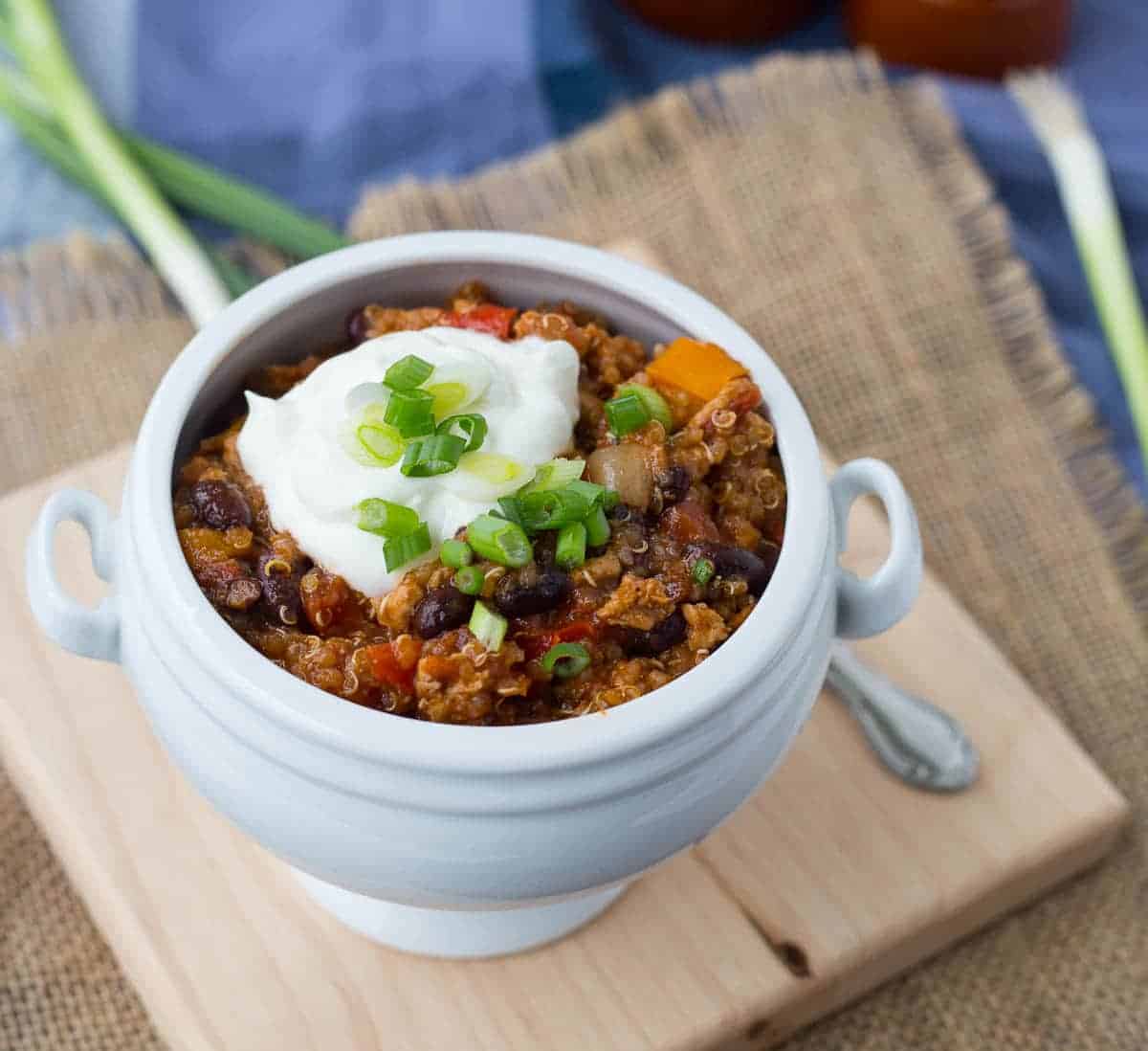 Quinoa chili in footed white bowl, with spoon.