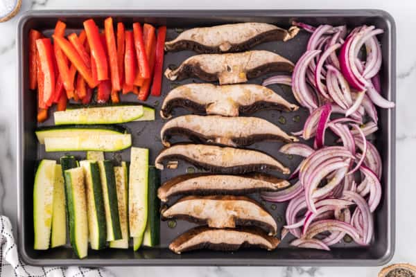 Sliced vegetables arranged on a sheet pan.