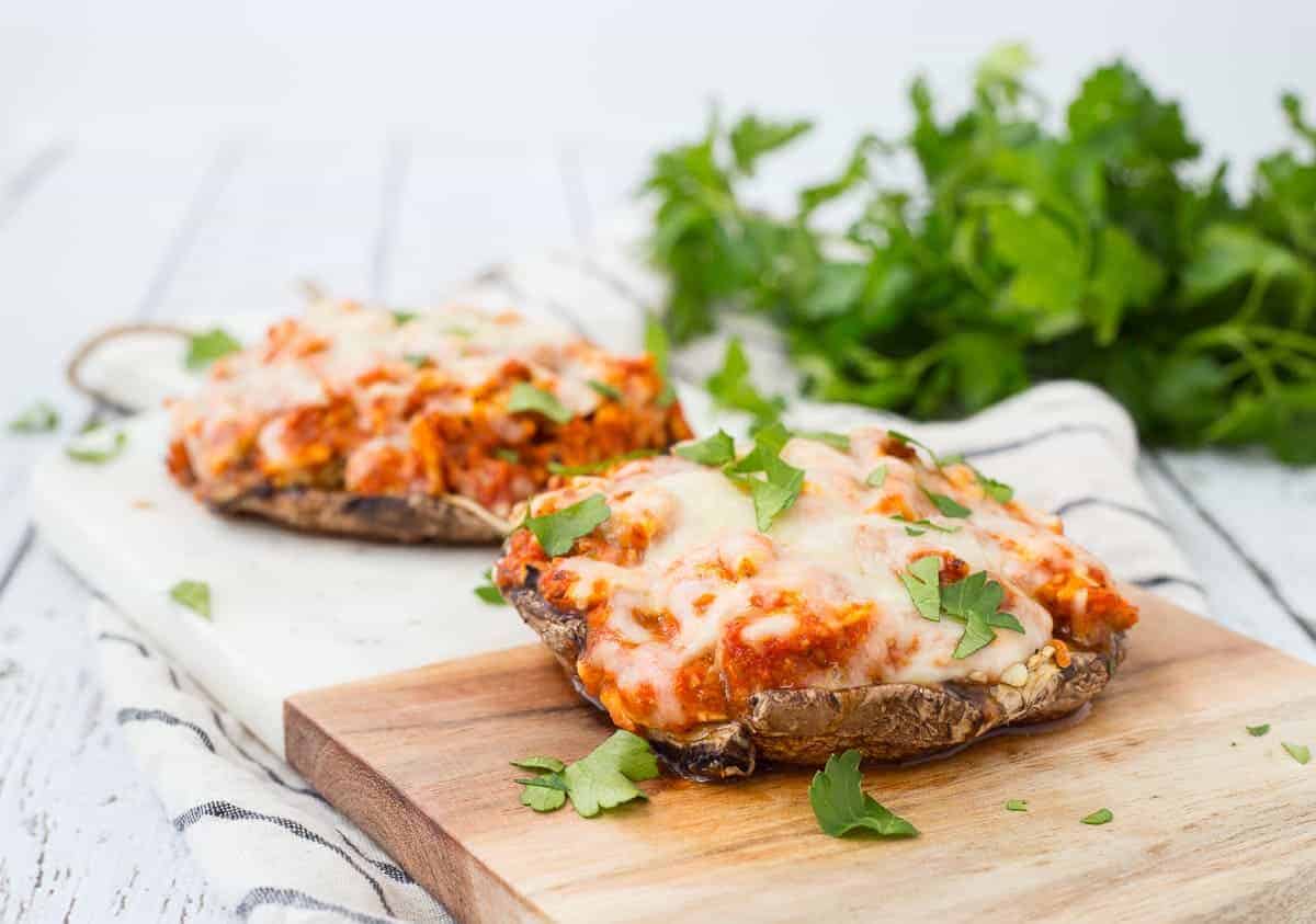 Front view of chicken Parmesan mushrooms on cutting board.