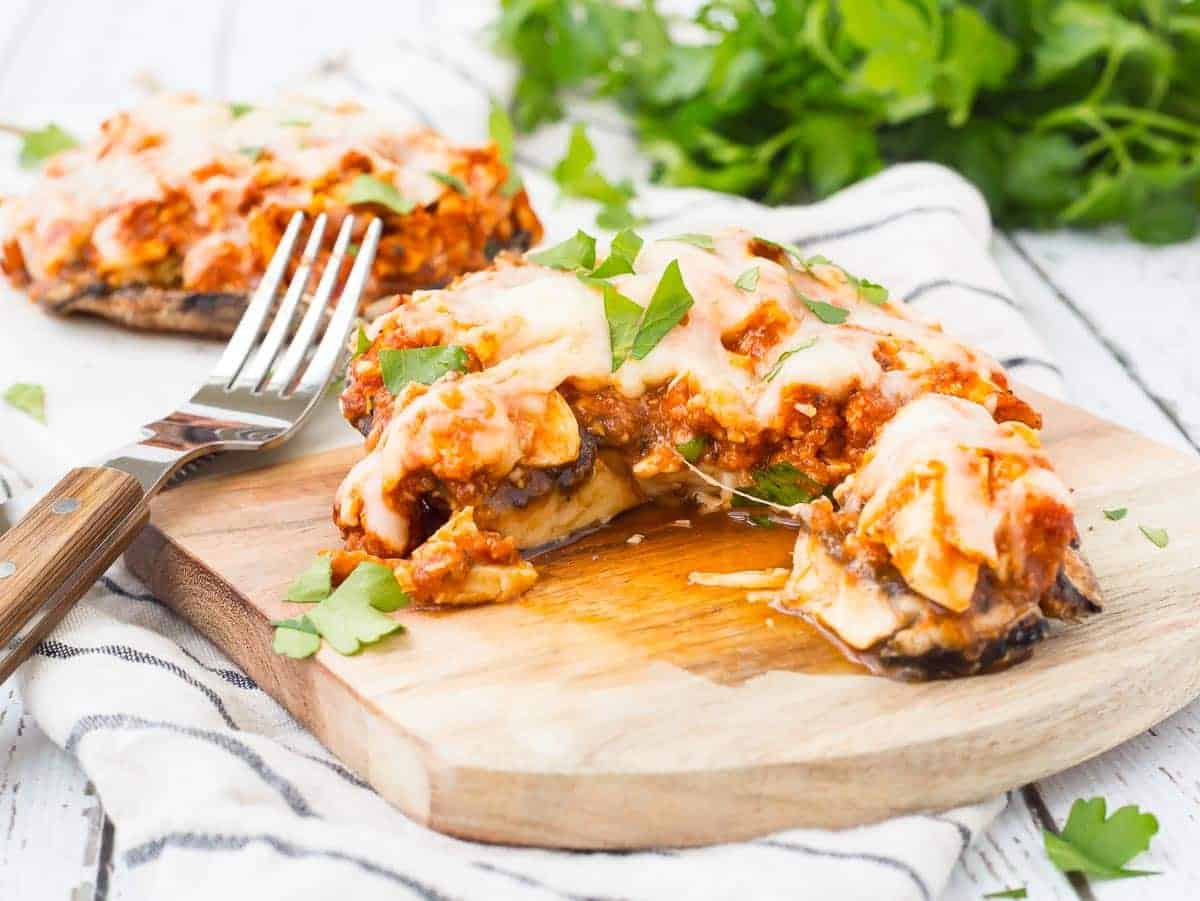 Stuffed mushroom on board, with portion removed. Fork alongside.