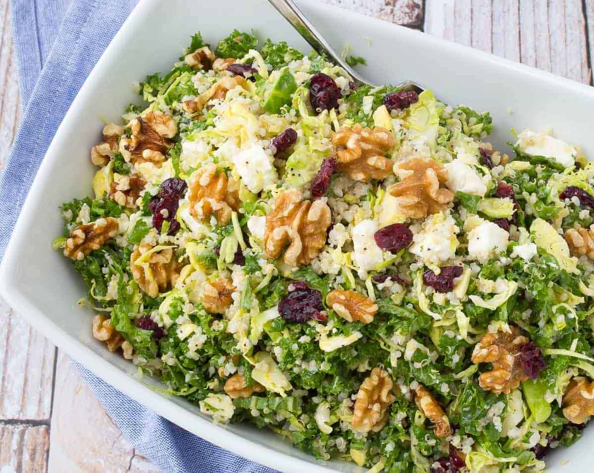 Overhead view of a kale salad in a bowl with cranberries, walnuts, and feta cheese.