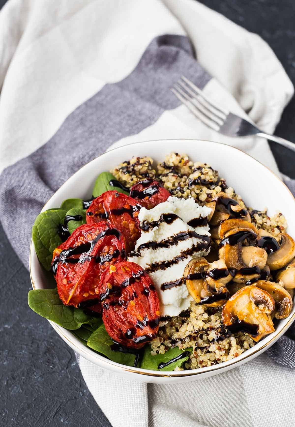 Overhead of round white bowl containing arranged salad with balsamic glaze drizzled over it. 