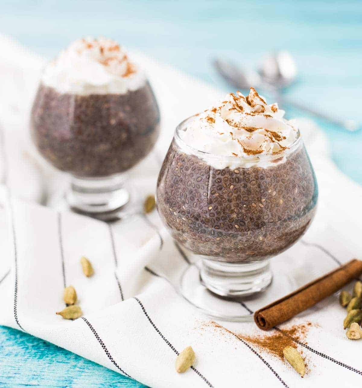 Clear glass stemmed serving bowls filled with chai chia seed pudding, topped with 