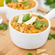 Chili in white bowl with handle garnished with parsley leaves.