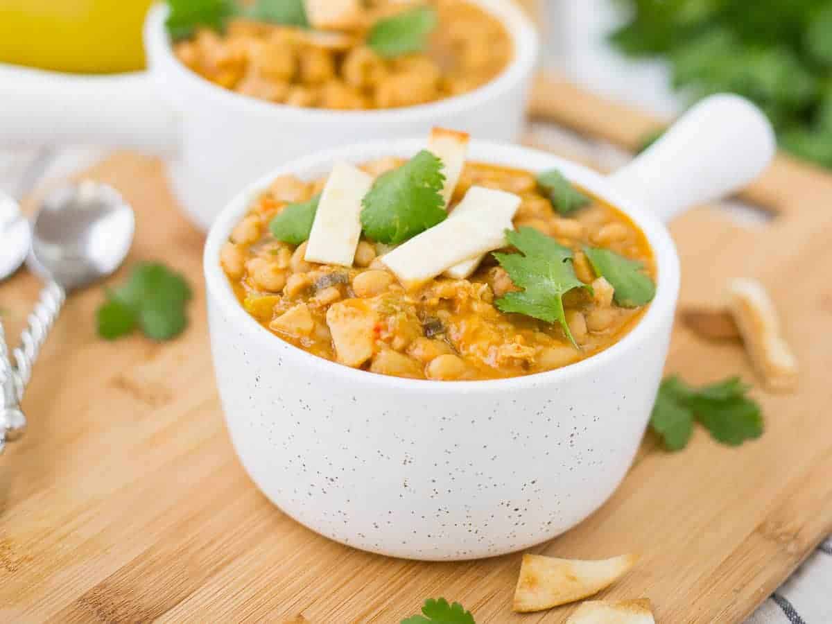 Closeup of chili in bowl, garnished with parsley leaves and tortilla strips.