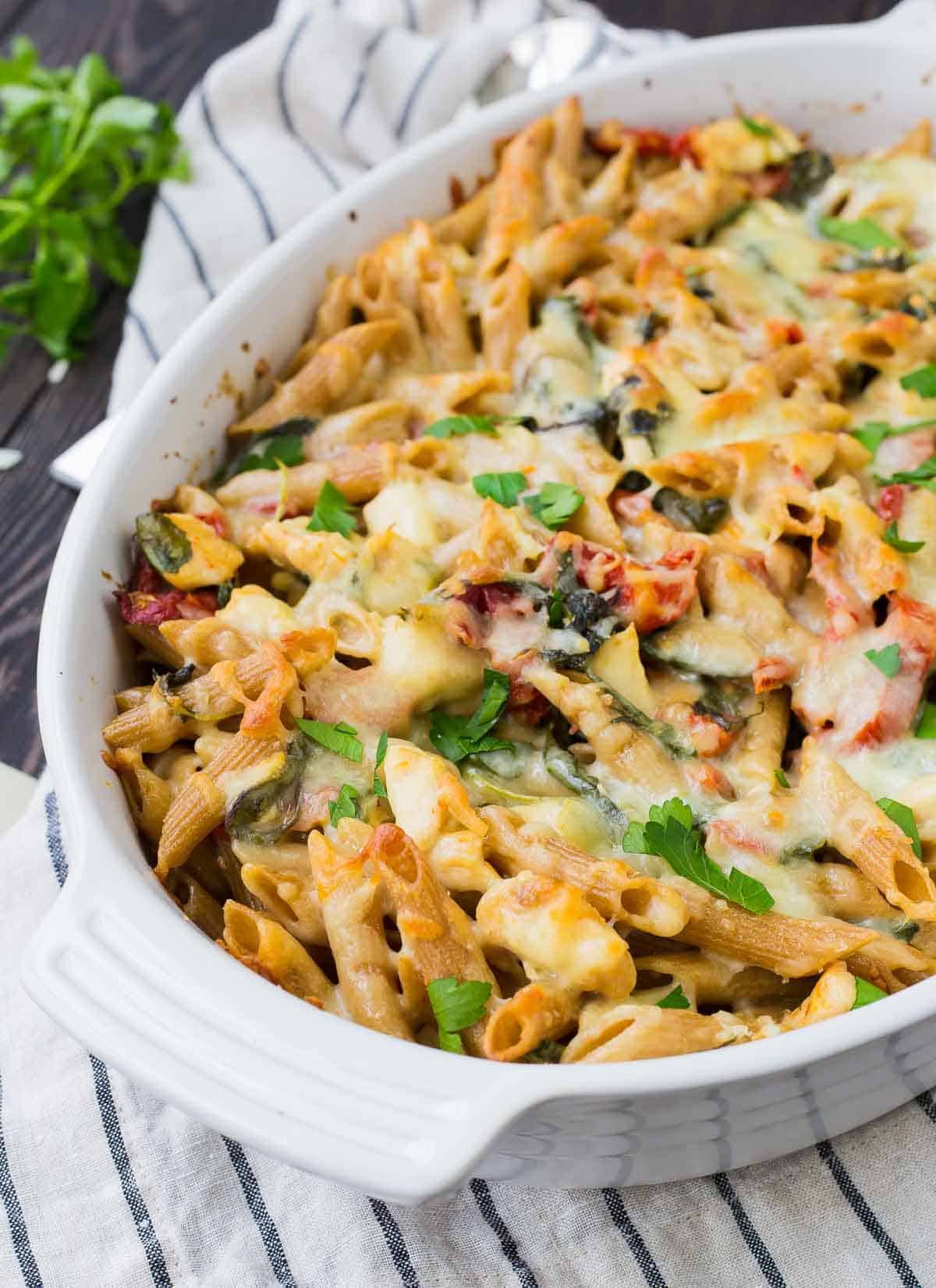 Partial overhead of baked pasta in white oval casserole dish.