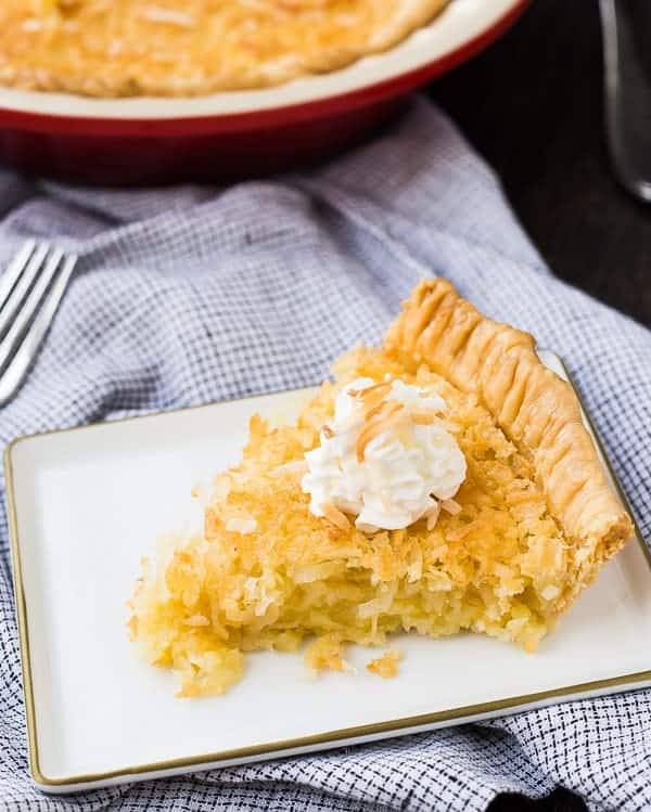 Slice of coconut custard pie with whipped cream on top.