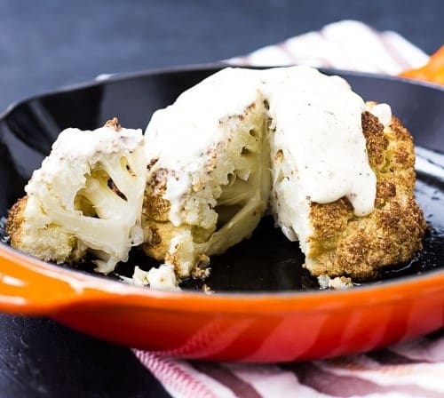 Roasted cauliflower with sauce in orange skilet.