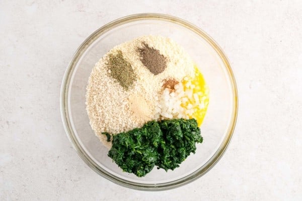 Spinach ball ingredients combined in a glass bowl.