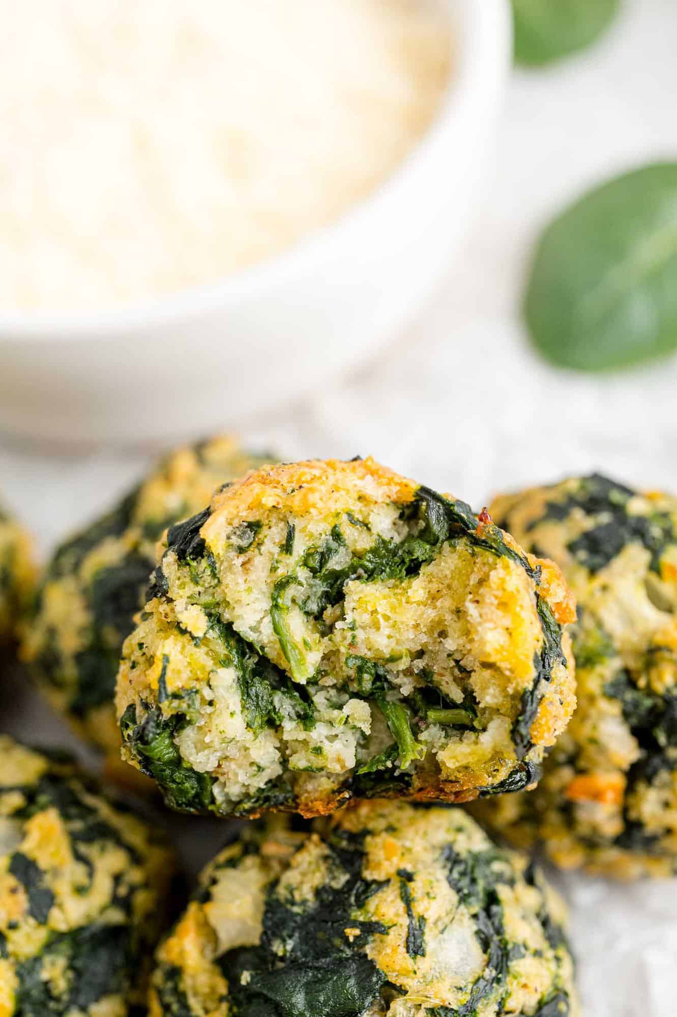 A small pile of spinach balls next to a bowl of dipping sauce.