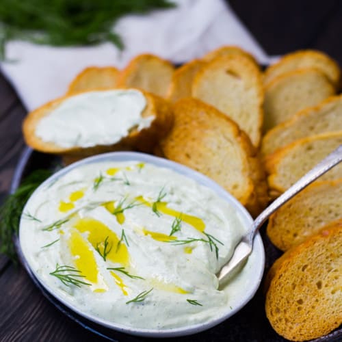 Whipped feta with lemon and dill is the perfect summer spread! Classy and sophisticated with the bright flavors of lemon, it's perfect spread on a crisp slice of French bread! Get the easy recipe on RachelCooks.com!