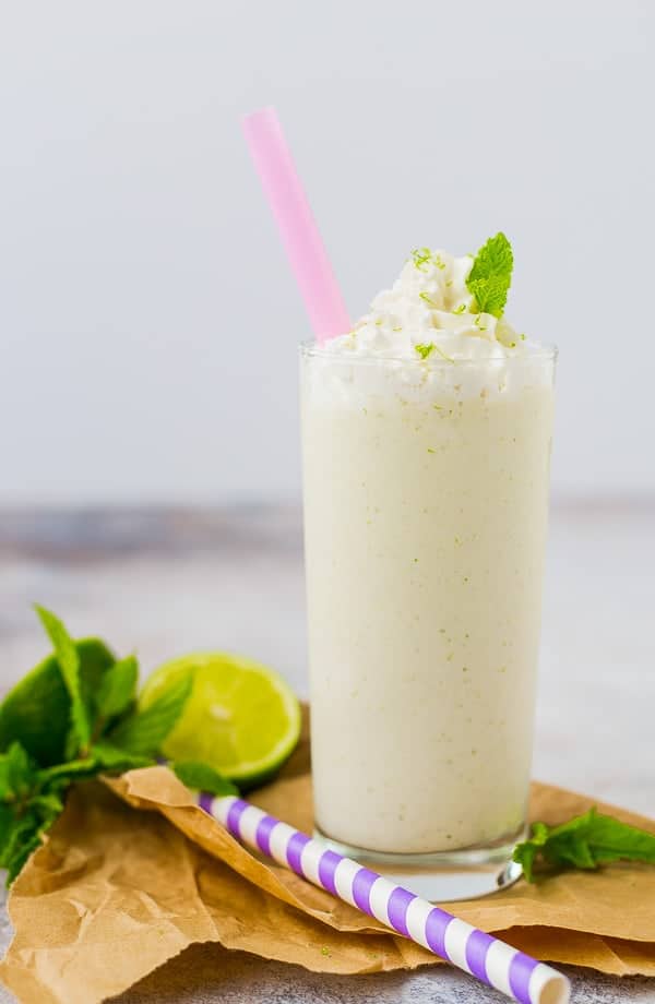 Mojito milkshake in a tall glass with a pink straw.