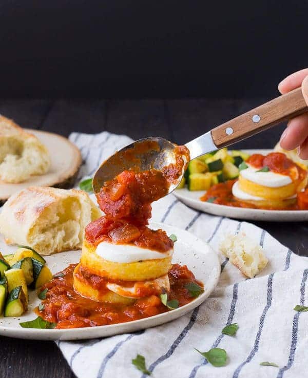 Sauce being spooned onto a polenta stack.