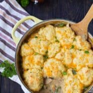 Overhead of Dutch oven containing chicken stew with cornmeal biscuits.