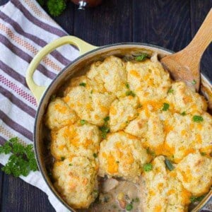 Overhead of Dutch oven containing chicken stew with cornmeal biscuits.