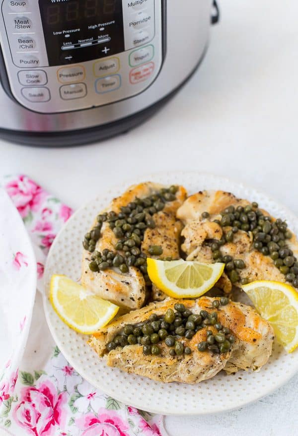 Overhead view of chicken with capers and lemon slices.