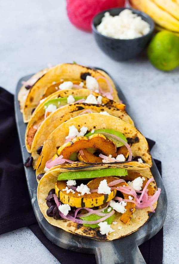 Tacos lined up on decorative black marble.