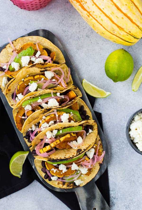 Overhead of tacos, with squash, limes, and cheese nearby.