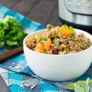 Farro stuffing in round white bowl garnished with fresh herbs.