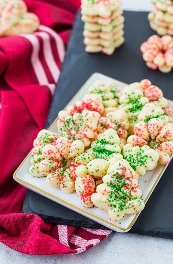 Cookies on plate, with other stacked around it, on slate.