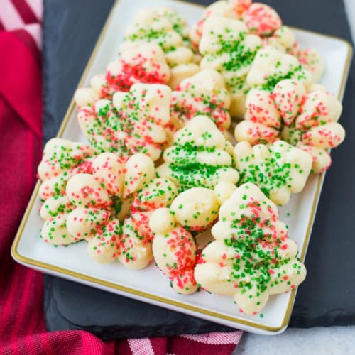 Front view of several spritz cookies on rectangular white plate.