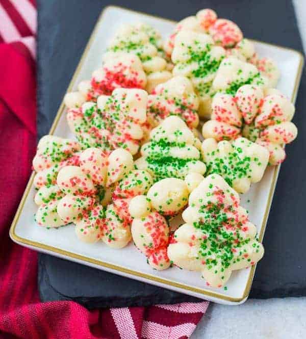 Several decorated spritz cookies on rectangular white plate.